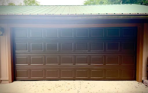 A brown garage door with a green roof is open.