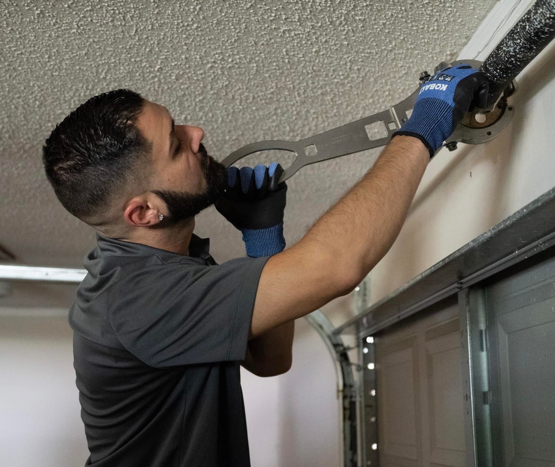 A man is working on a garage door with a wrench.