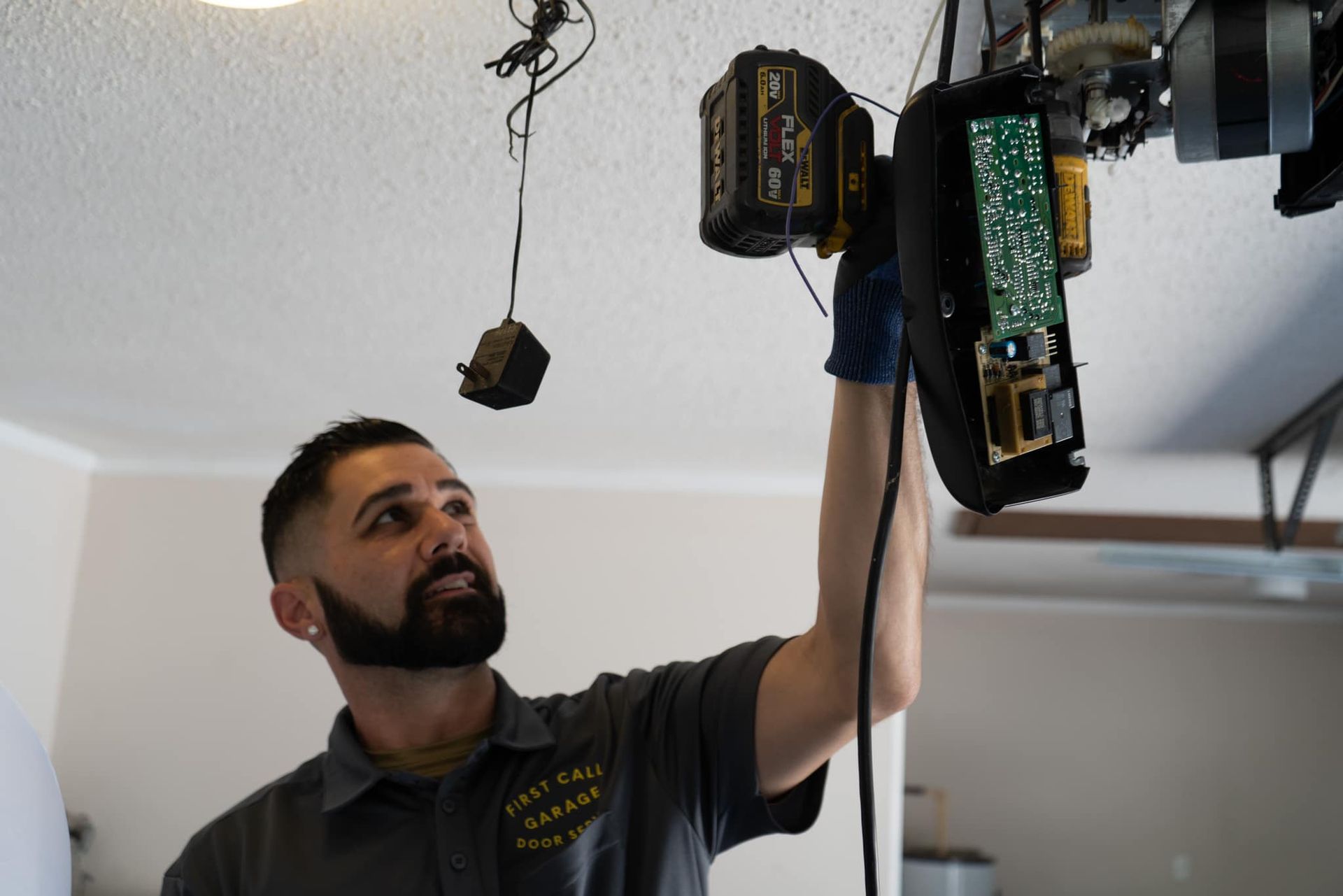A man is working on a garage door opener in a garage.