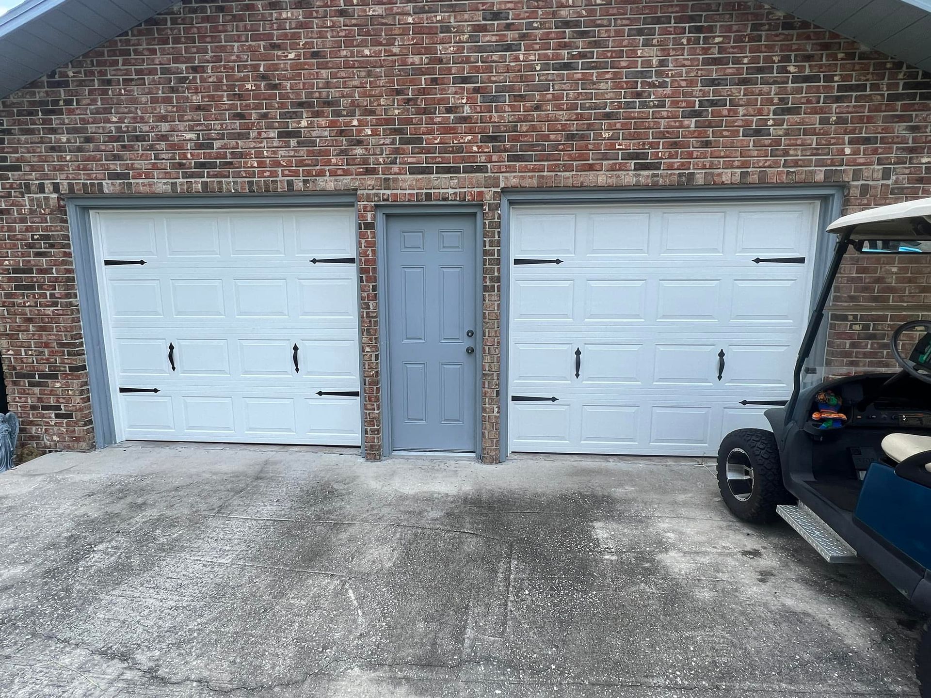 A golf cart is parked in front of a garage door.