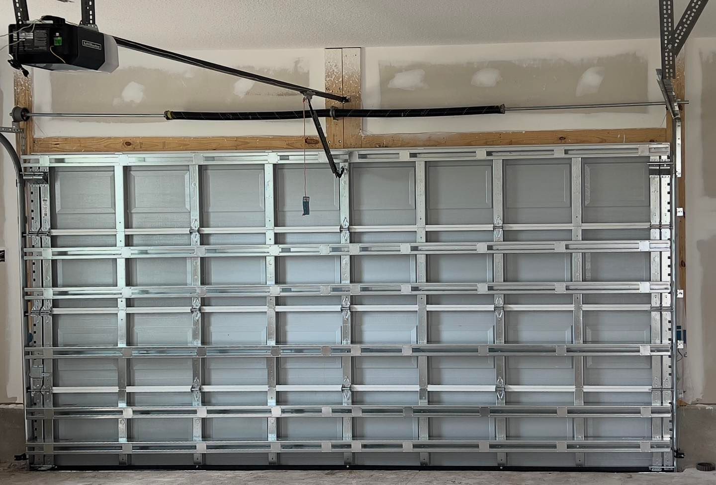 A garage door with a garage door opener hanging from the ceiling