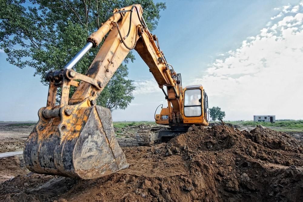 a yellow excavator is digging a hole in the dirt