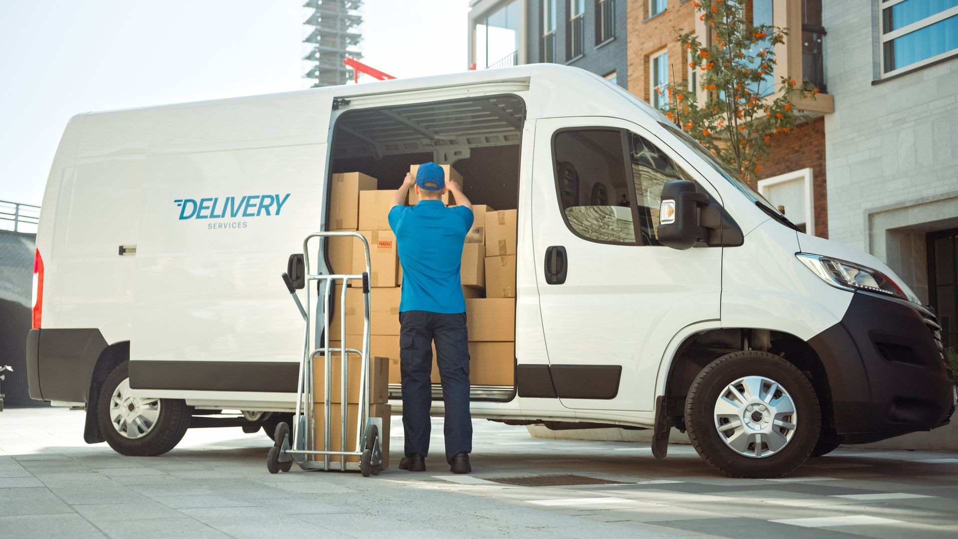 A delivery man is loading boxes into a delivery van.