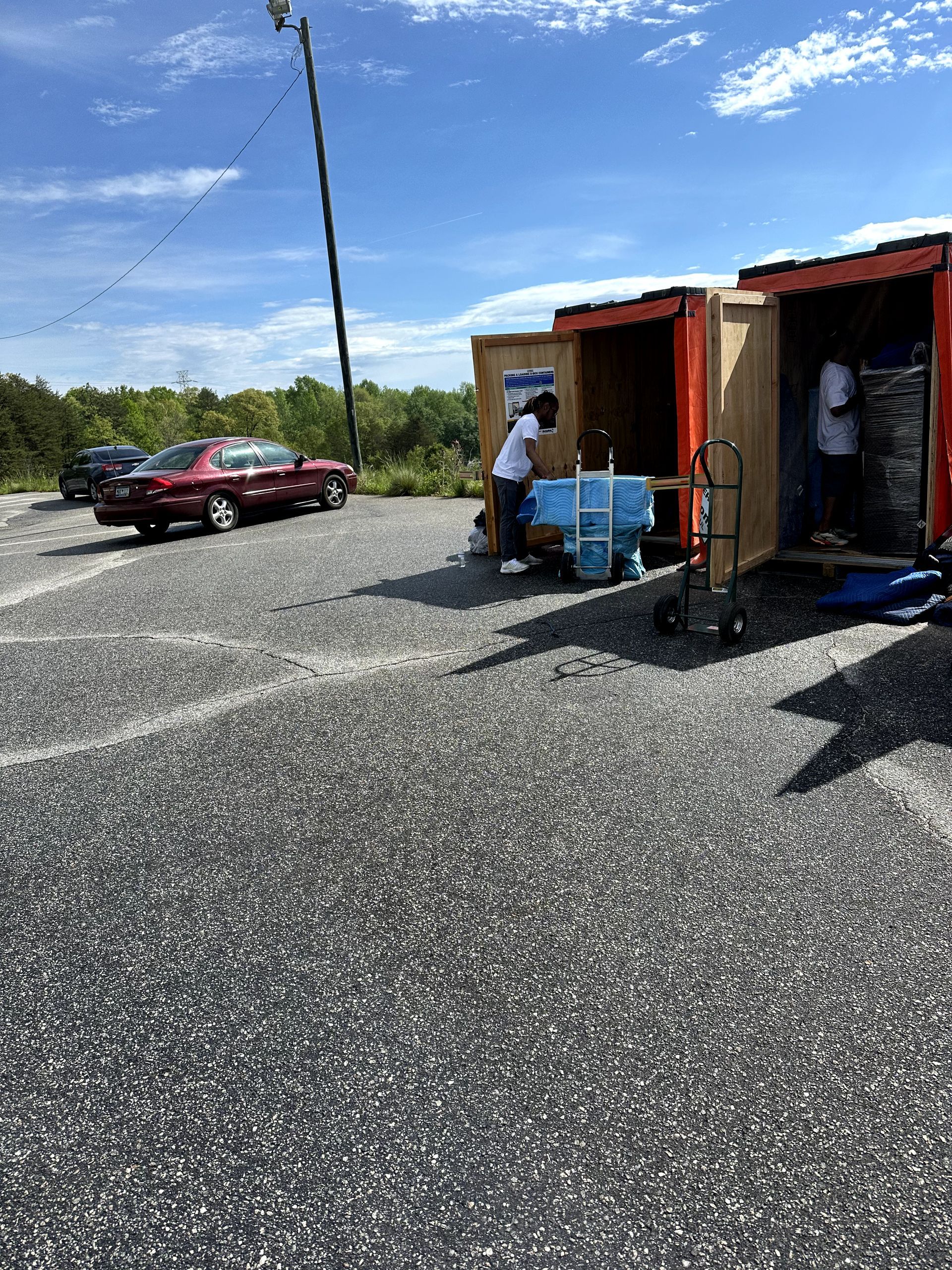 A man is loading a cooler into a shipping container in a parking lot.