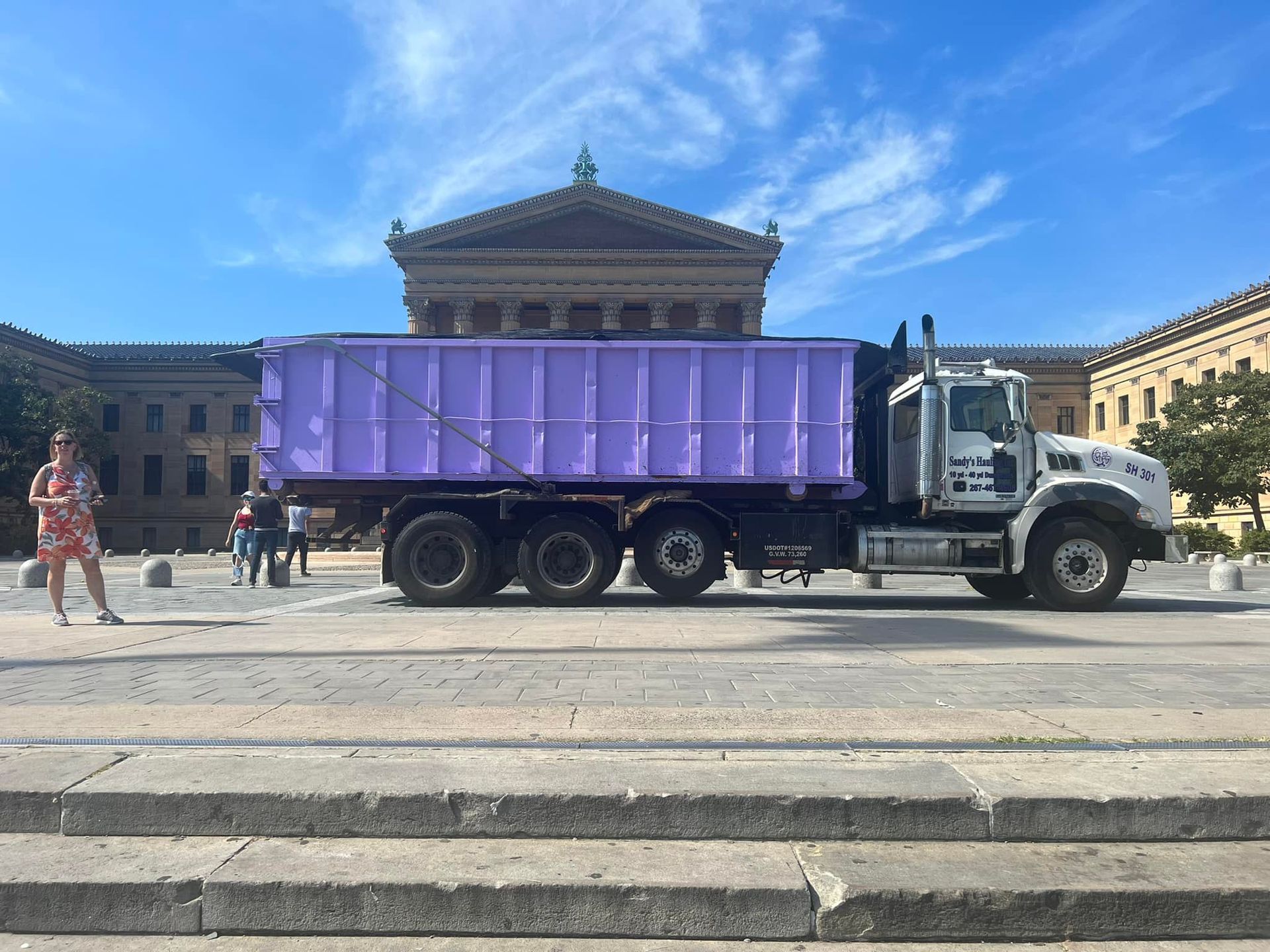 Purple dumpster truck in front of the Philadelphia Museum of Art on a sunny day.