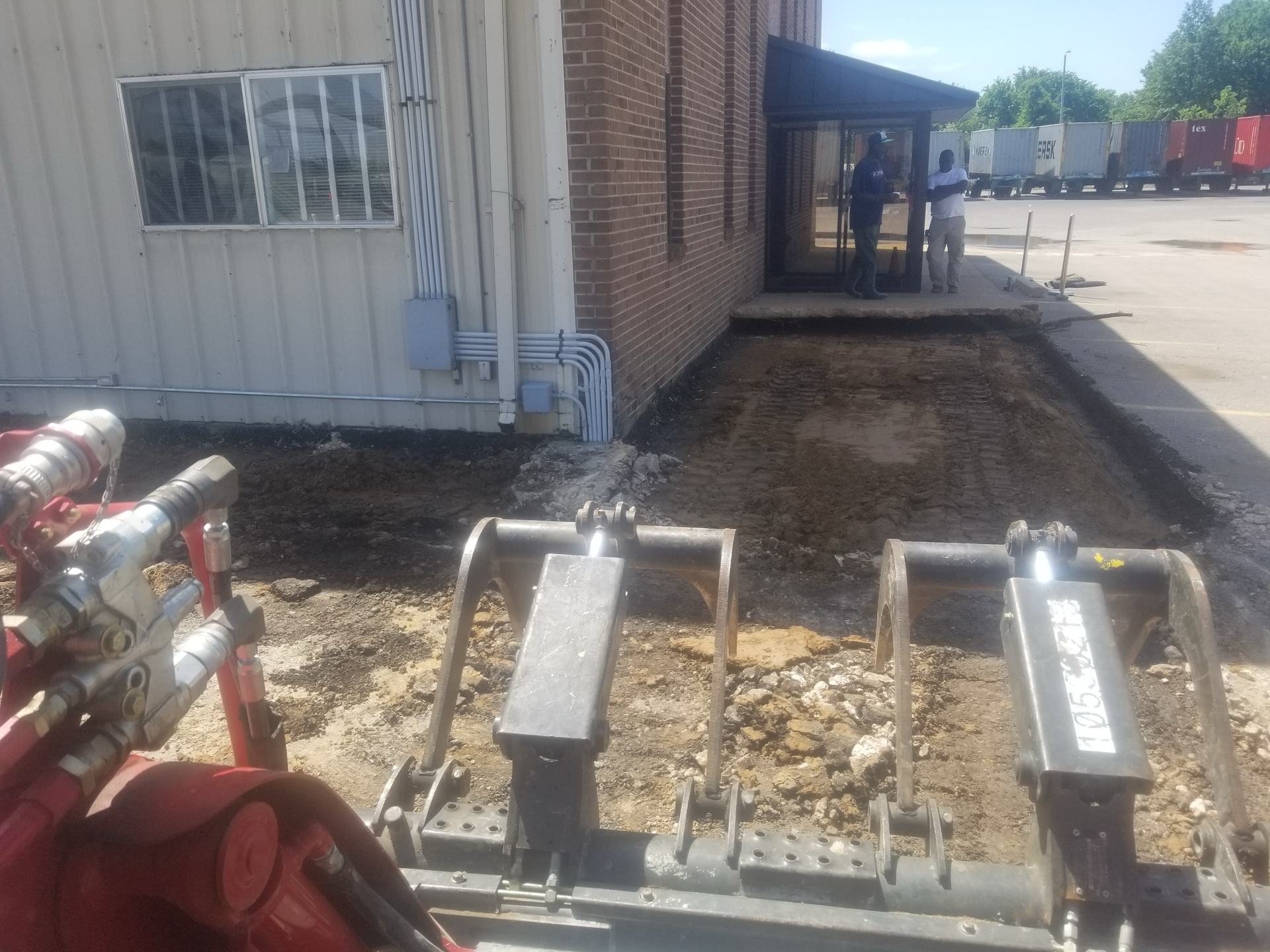 A bulldozer is parked in front of a brick building.