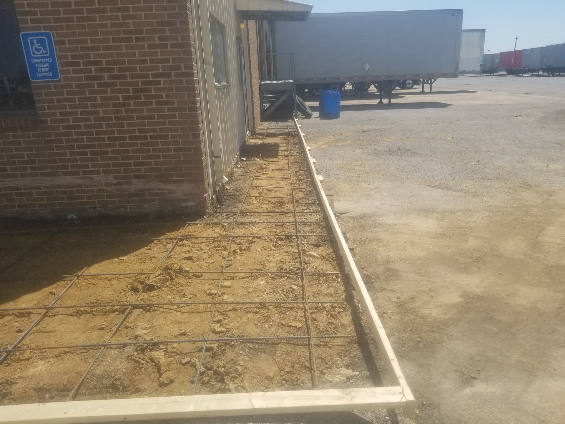 A concrete walkway is being built in front of a brick building.