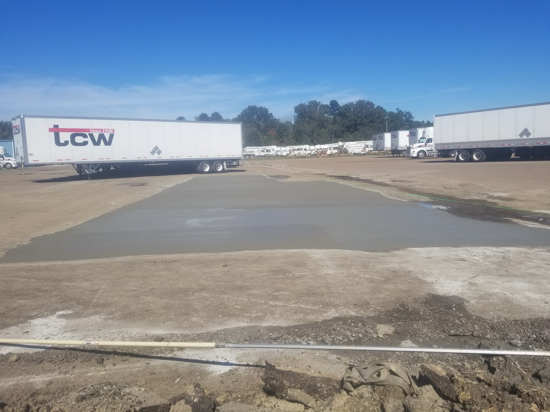 A couple of semi trucks are parked in a parking lot.