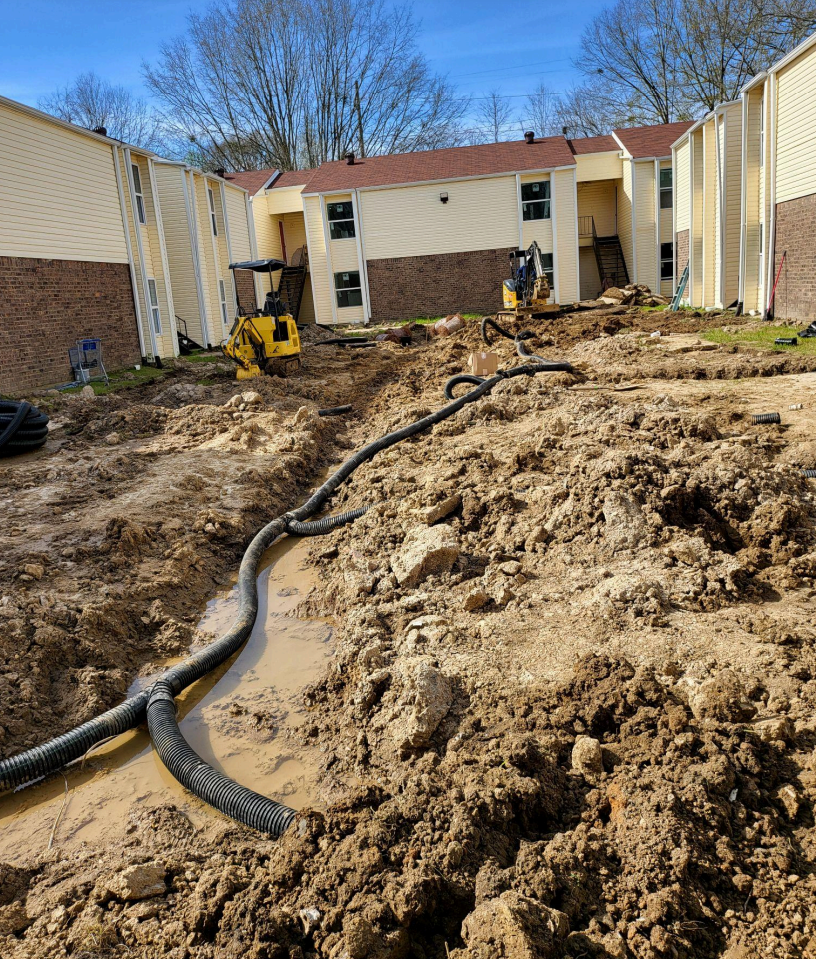 A construction site with a lot of dirt and a building in the background.