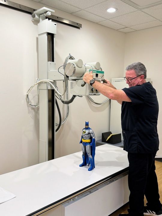 A man is taking an x-ray of a batman doll.