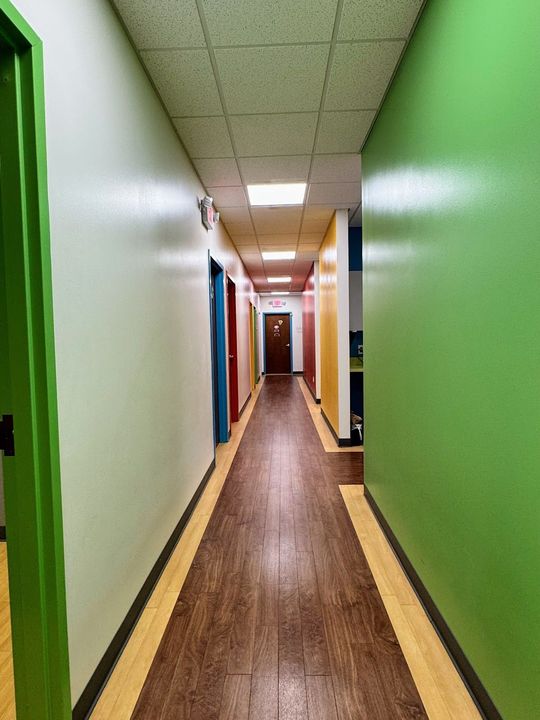 A long hallway with green walls and wooden floors