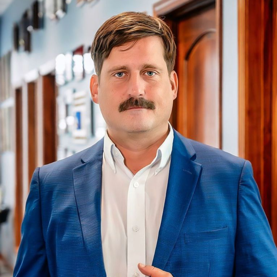 A man in a suit and striped shirt is smiling for the camera