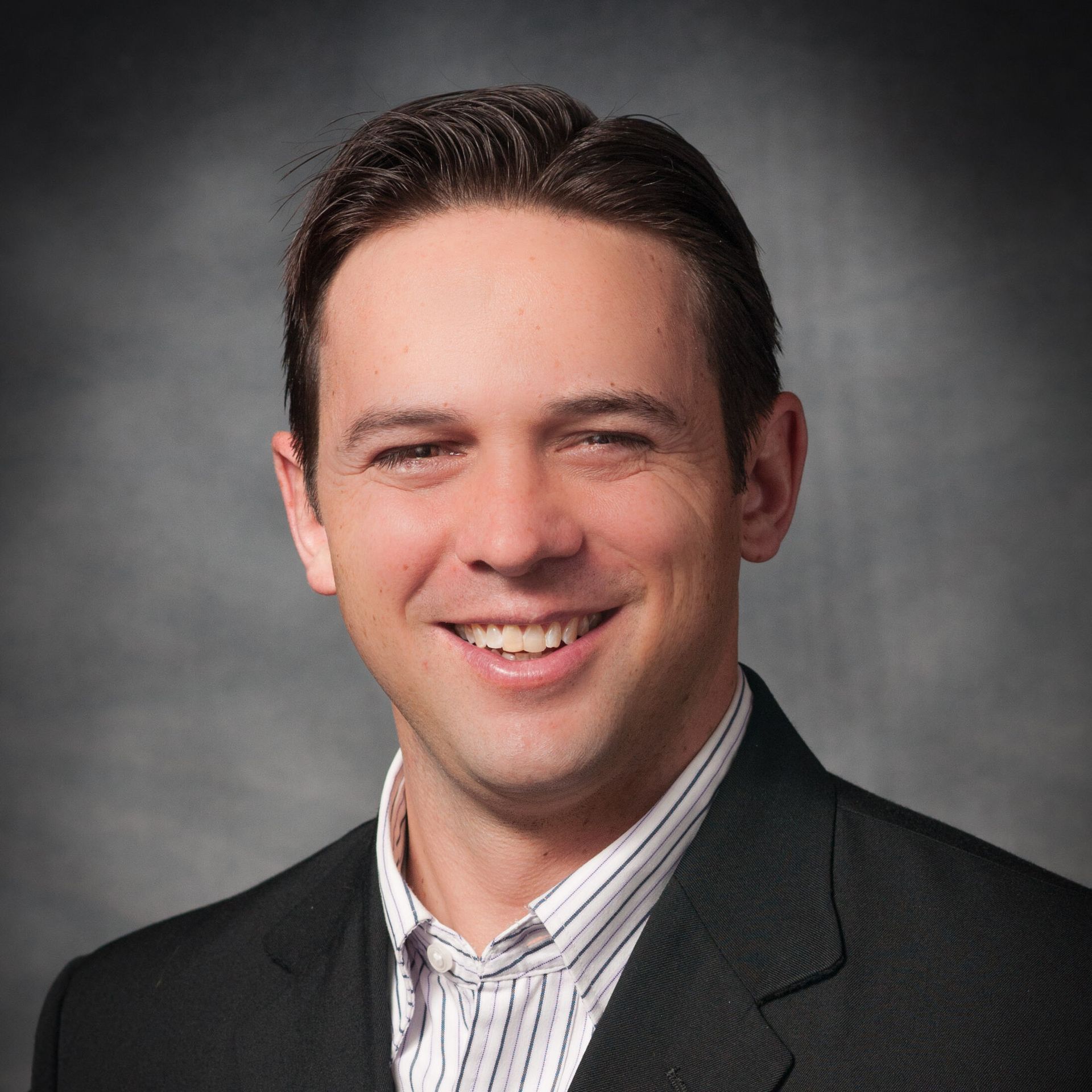 A man in a suit and striped shirt is smiling for the camera