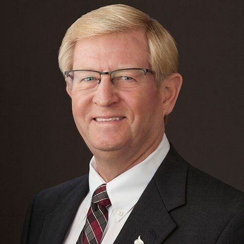 A man in a suit and tie is smiling for the camera