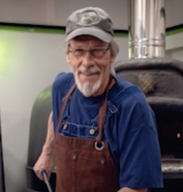 A man wearing an apron and a hat with the letter f on it