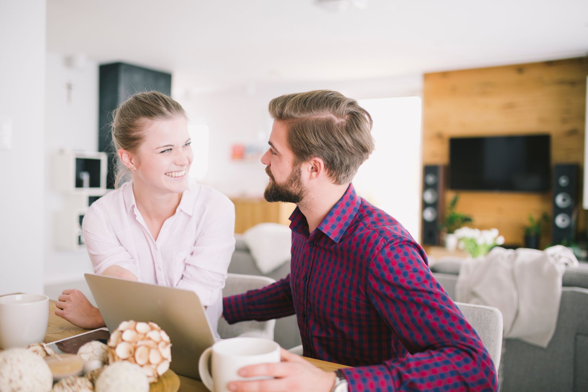A man and a woman are sitting at a table with a laptop.