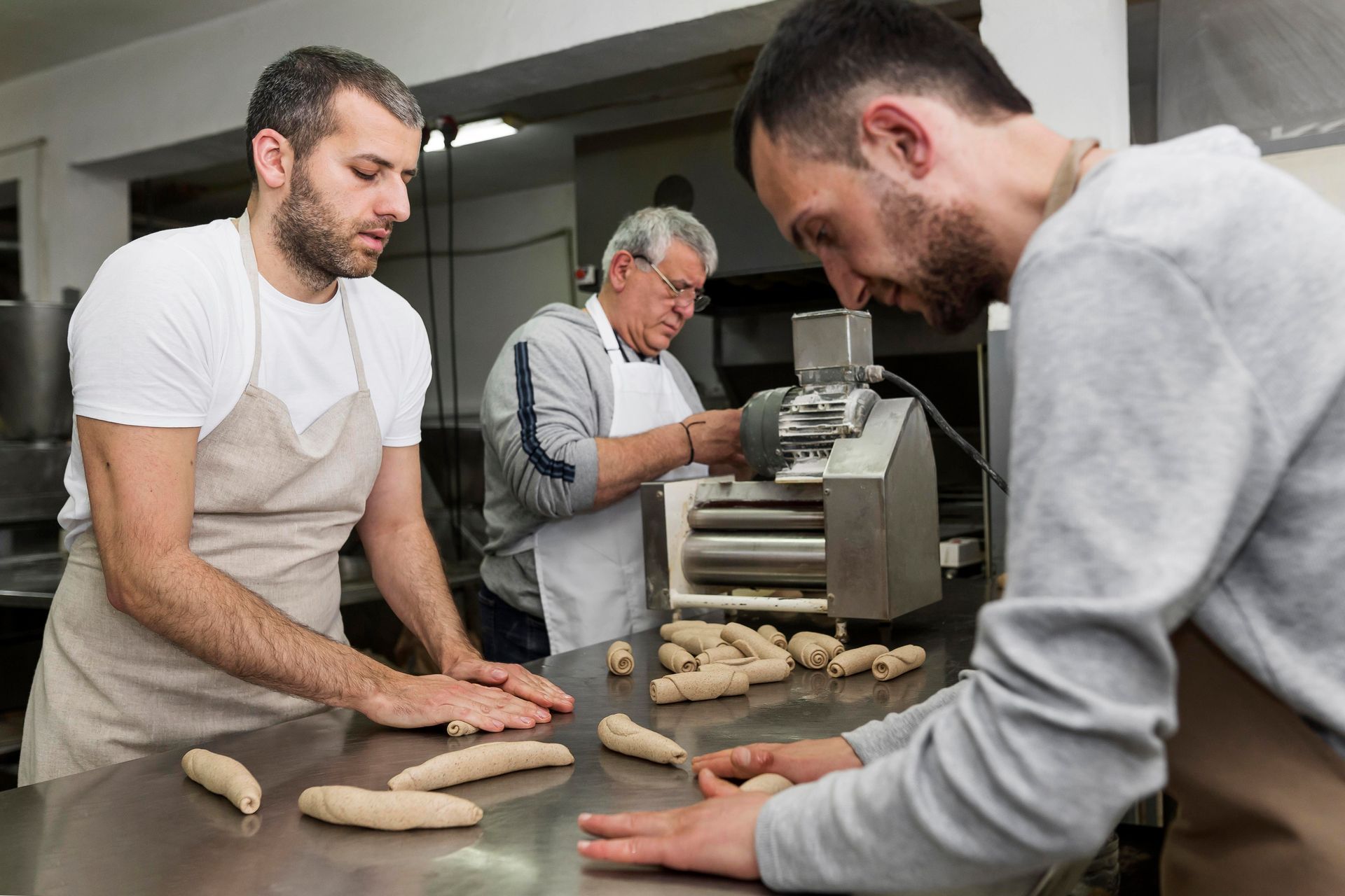Three men are working in a bakery making dough.