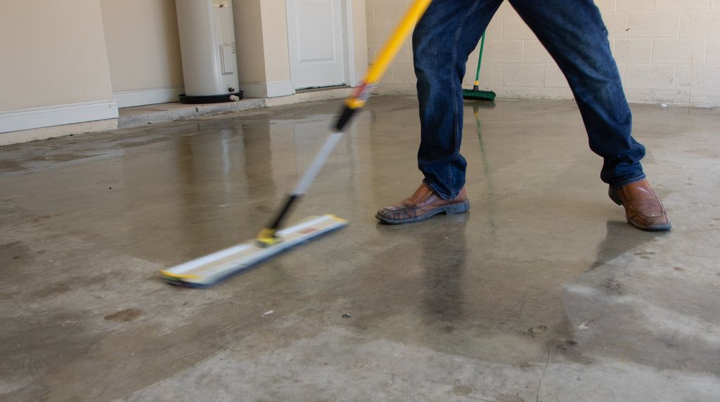 A concrete flooring contractor cleaning stains from a concrete foundation.