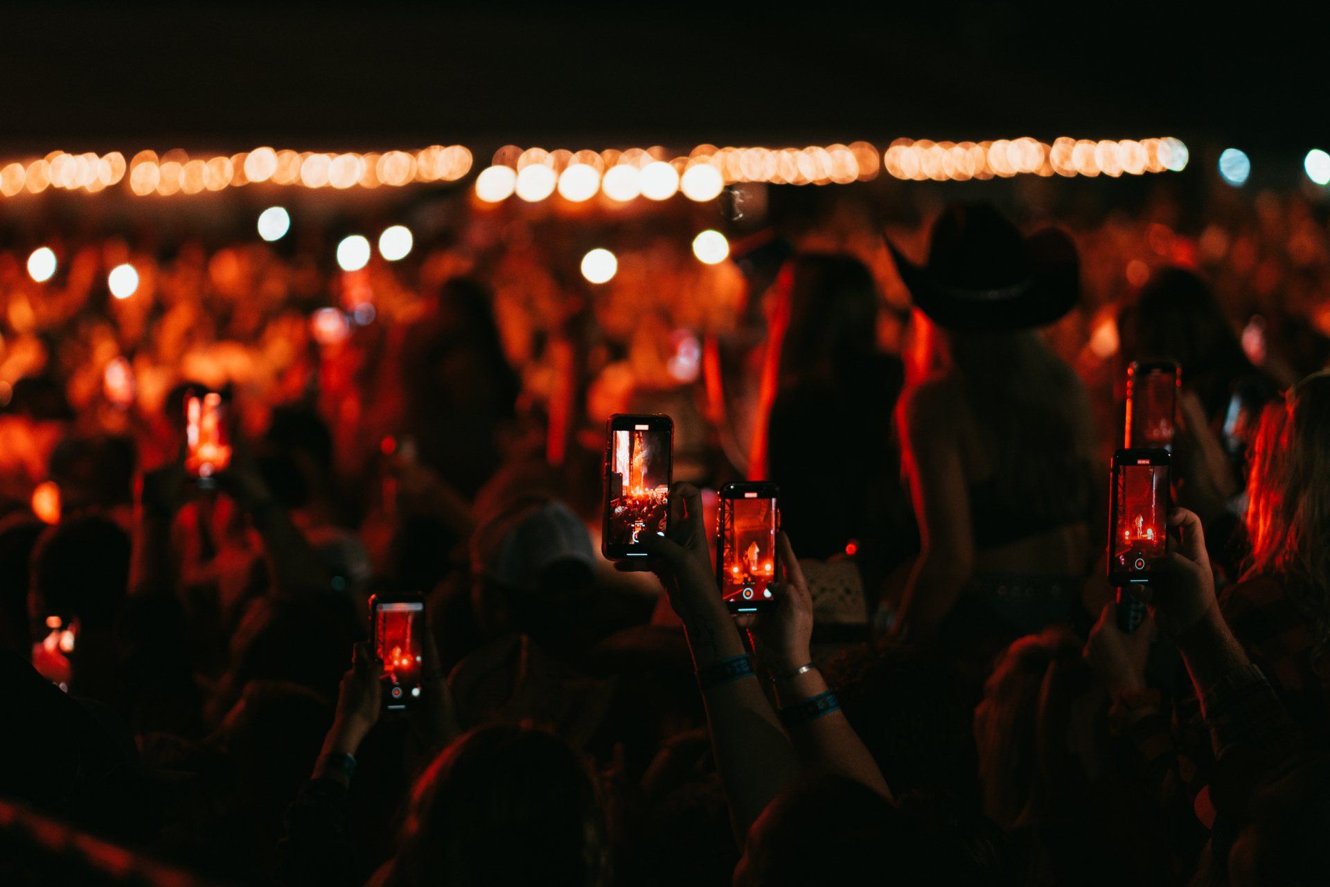 people at live country music concert recording with phones