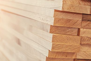 A stack of light-colored, sawn wooden planks arranged in neat horizontal layers.