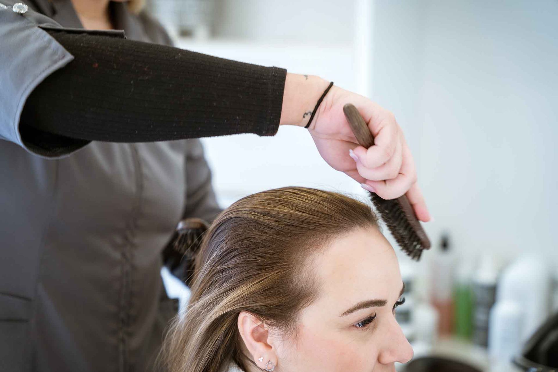 Hairdresser brushing a client's hair in a salon; close-up view.