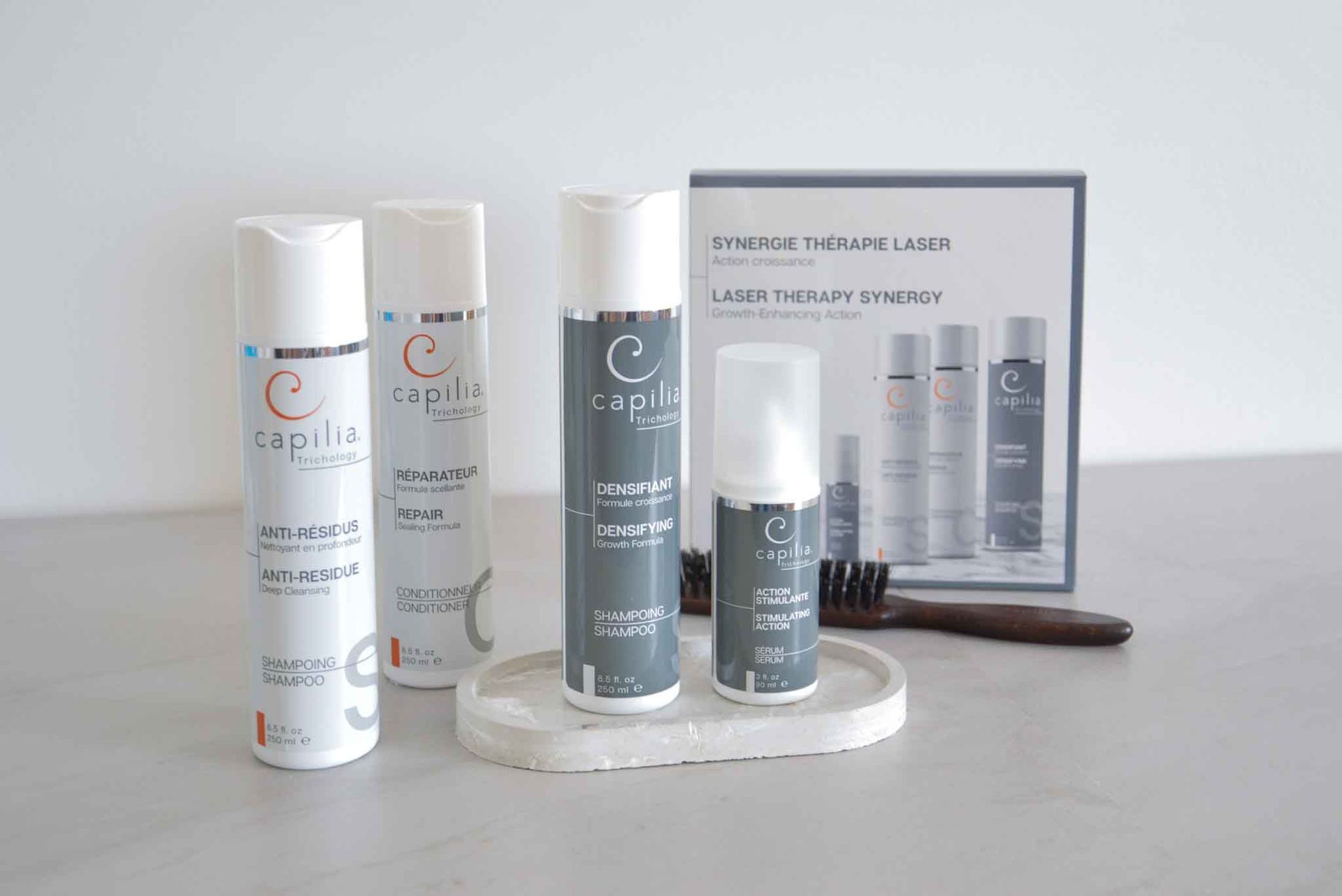 Hair care products and laser therapy set on a white surface, with a brush.