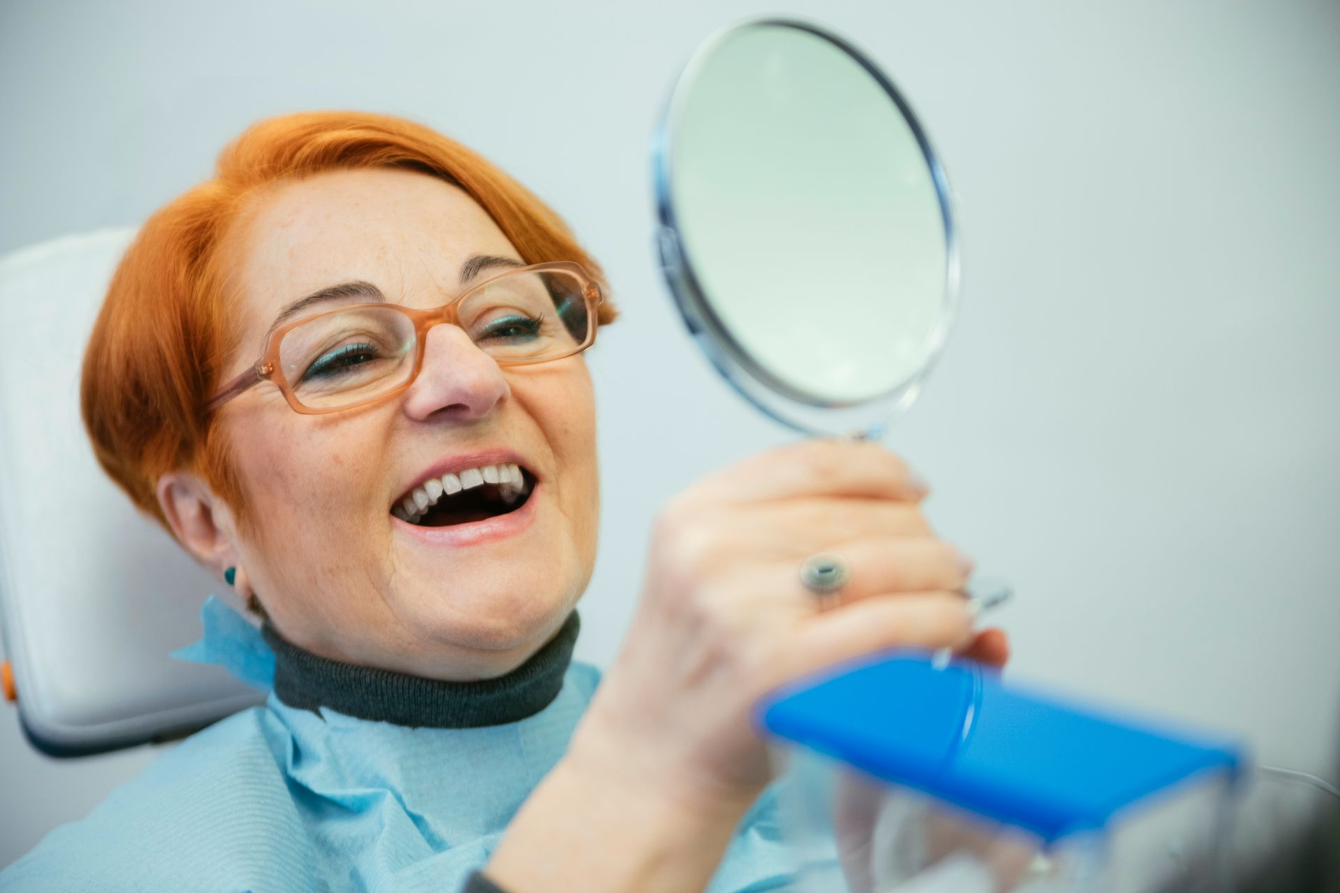 Dentist smiling while holding a dental mirror in a clinic