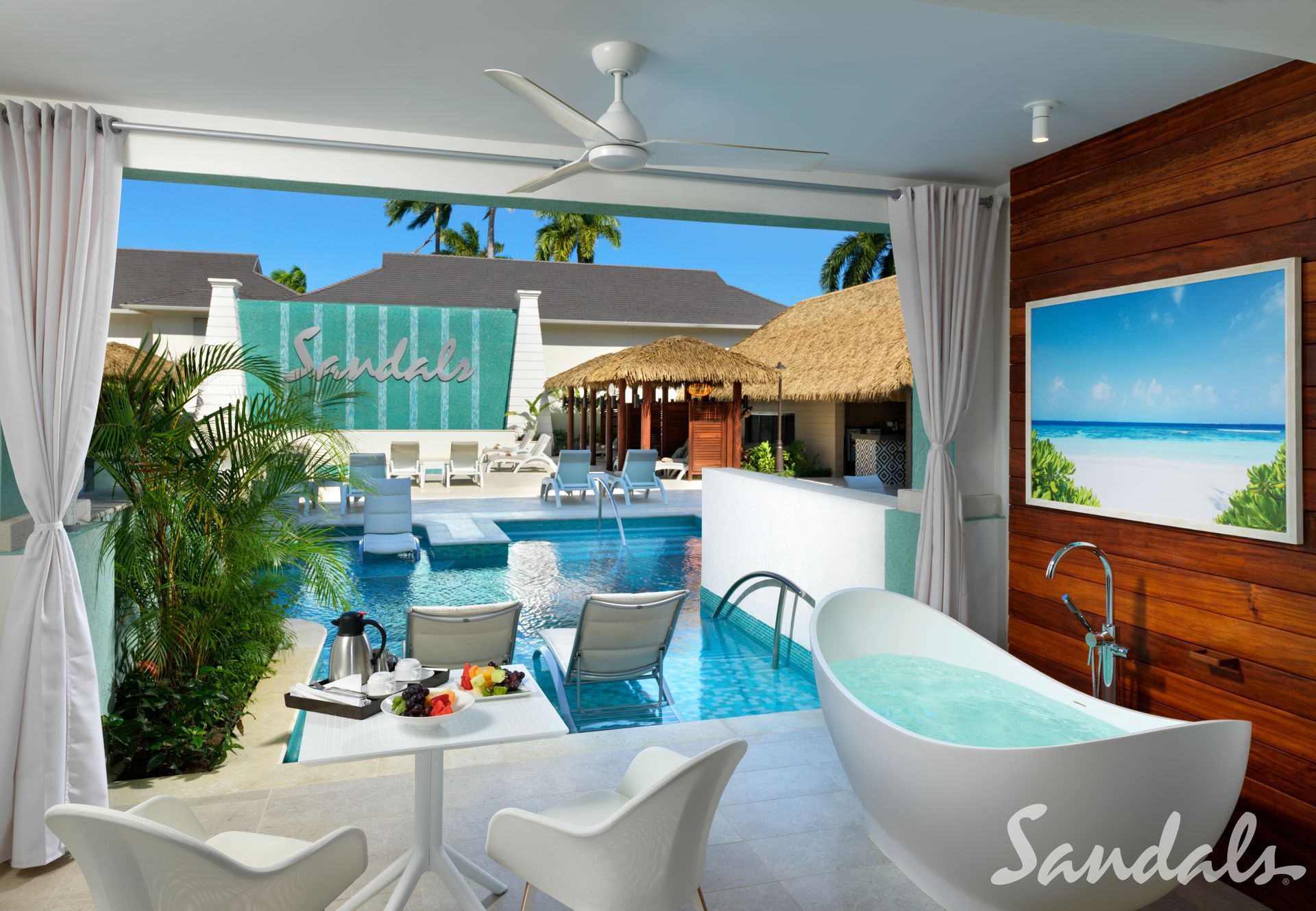 A sandals hotel room with a bathtub and a swimming pool