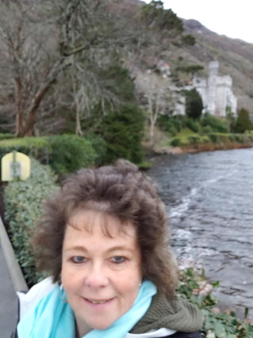 A woman is smiling in front of a body of water