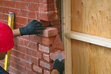 man in red hat building a wall