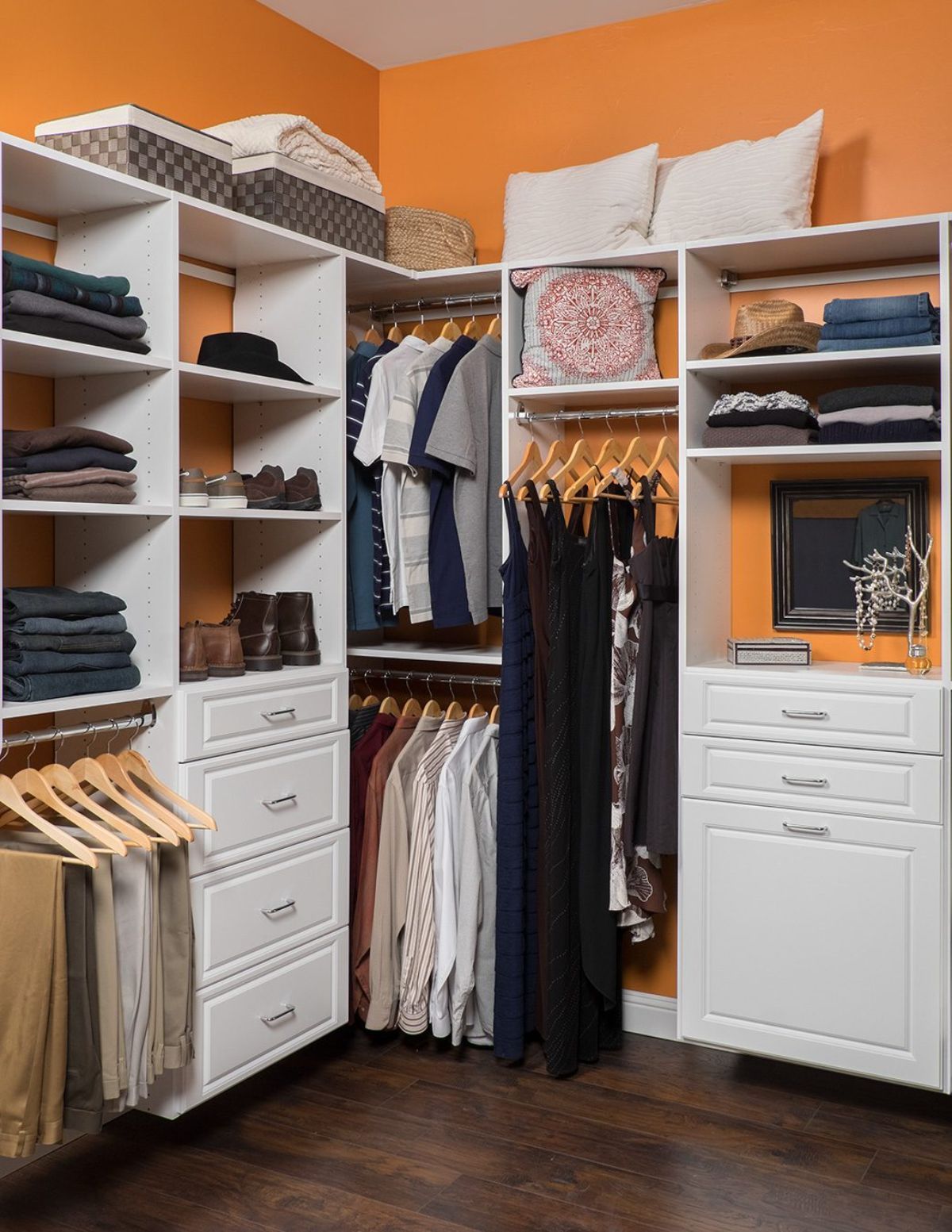 A walk in closet with orange walls and white shelves