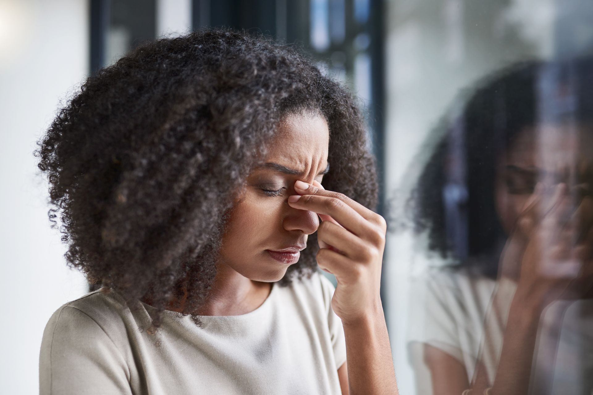 A woman is holding her nose because she has a headache.