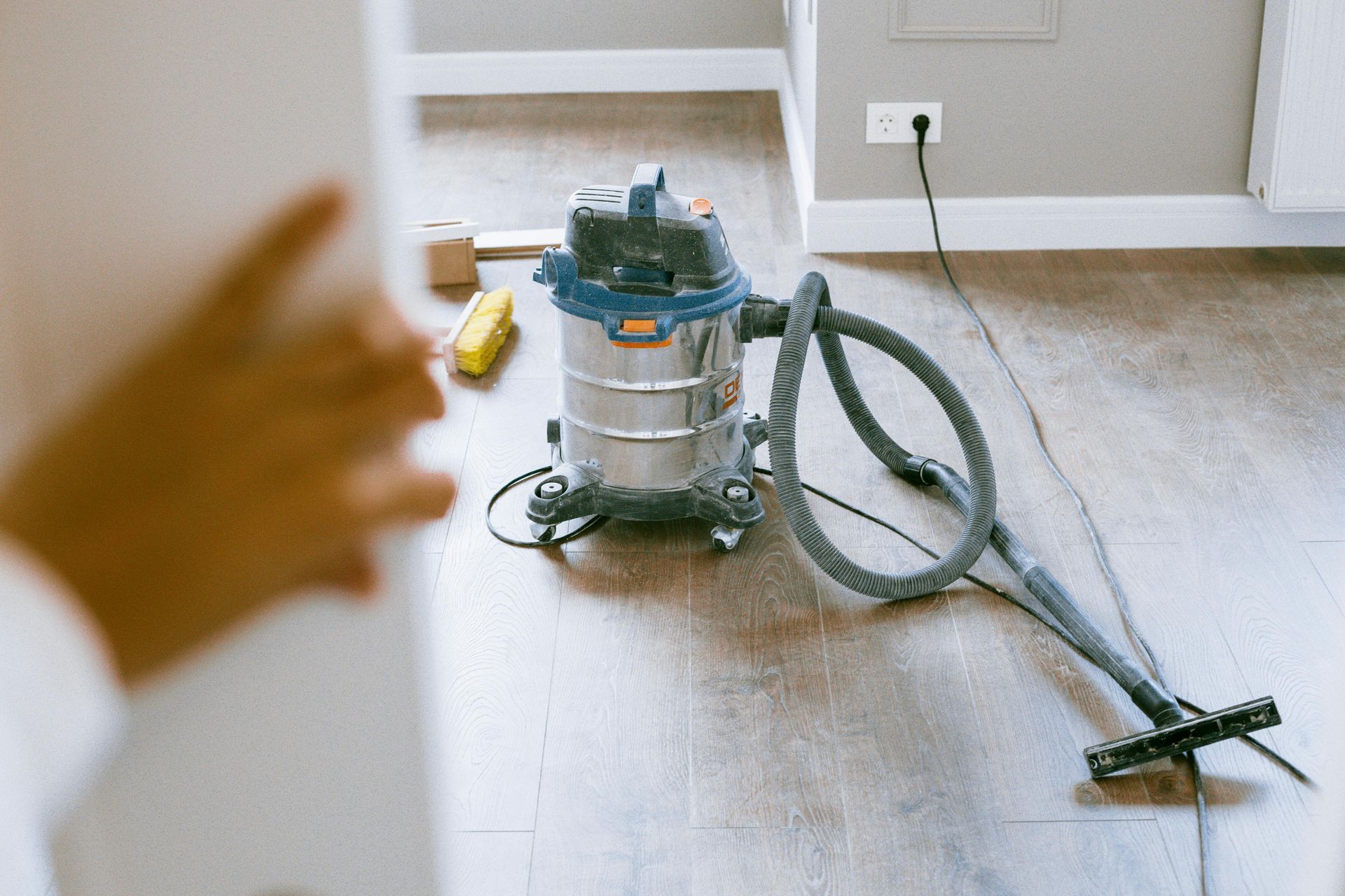 A vacuum cleaner is sitting on a wooden floor in a room.