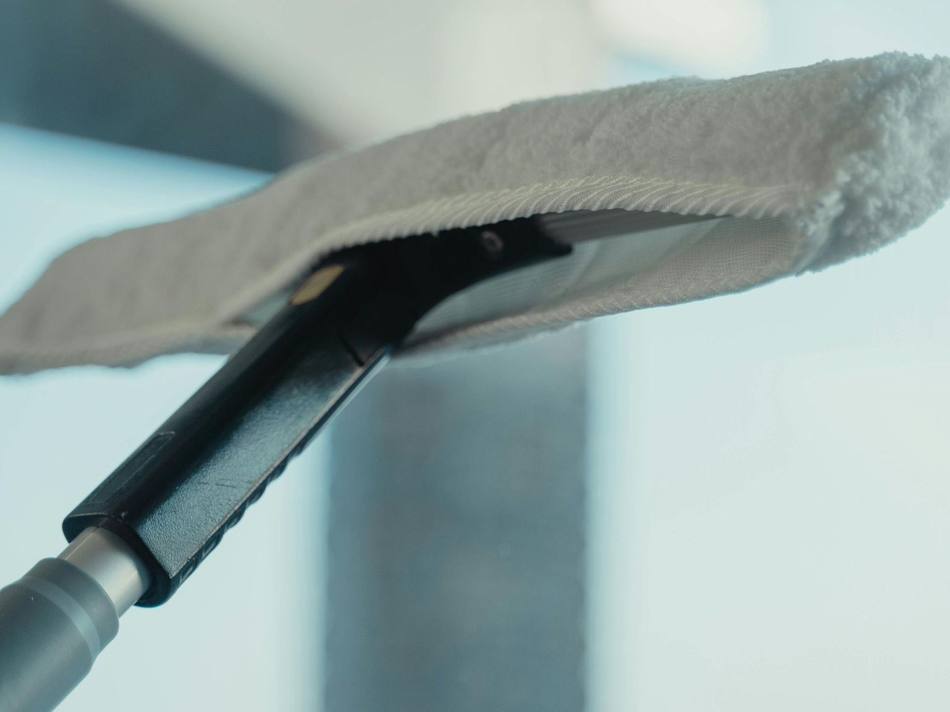 A close up of a mop being used to clean a window