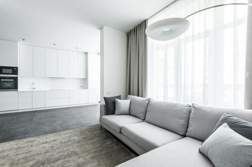 A living room with a couch and a kitchen in the background.