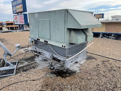 A large air conditioner is sitting on top of a gravel roof.