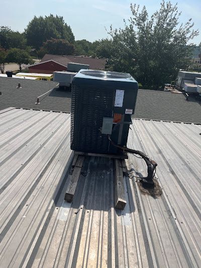 A large air conditioner is sitting on top of a metal roof.