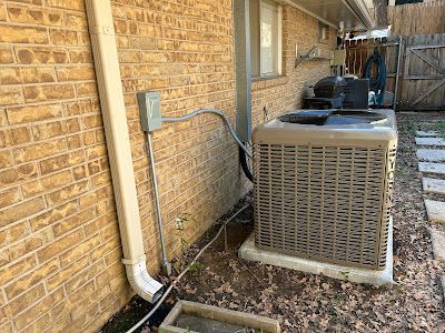 An air conditioner is sitting on the side of a brick building.