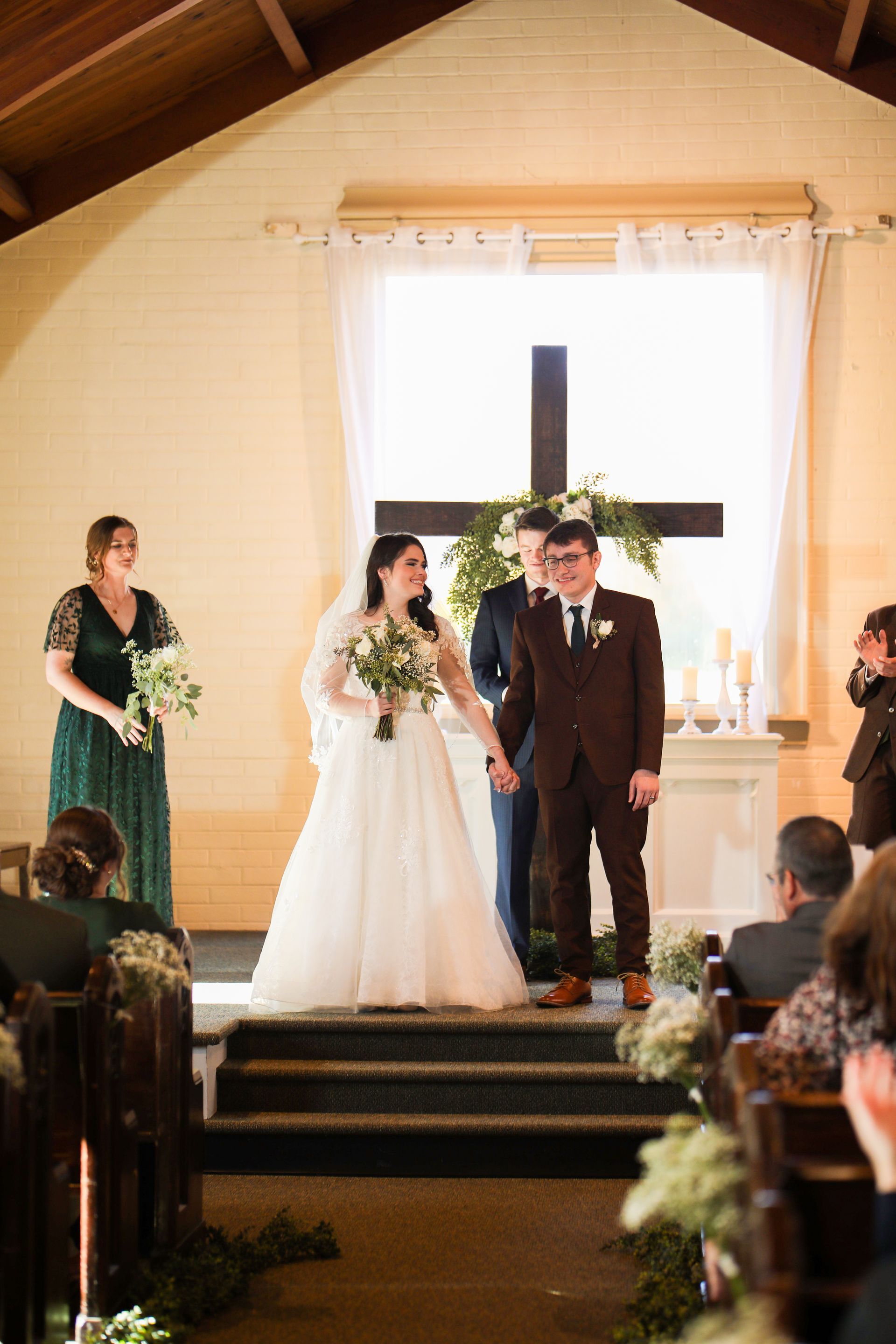 A bride and groom are holding hands during their wedding ceremony in a church.
