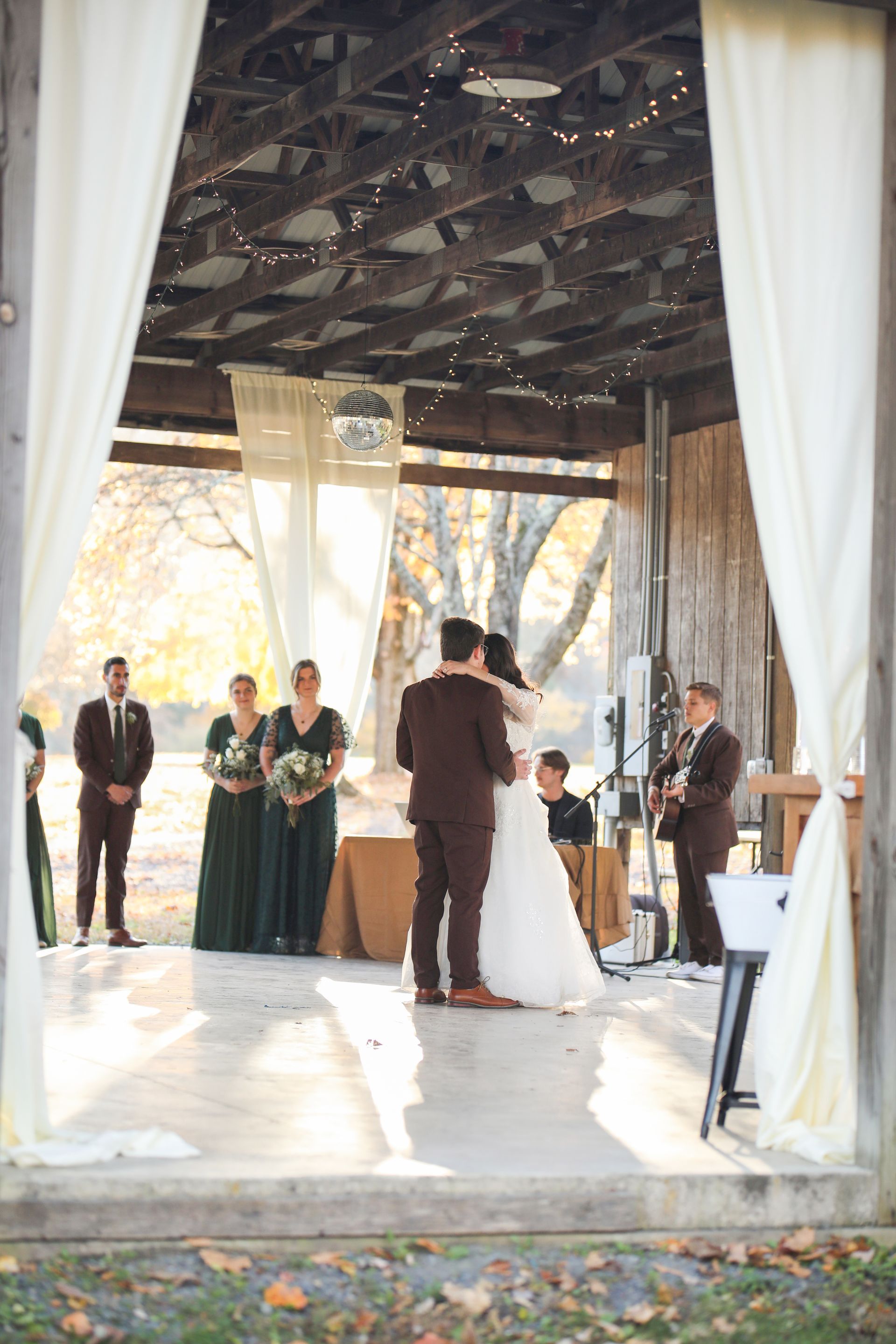 A bride and groom are kissing during their wedding ceremony in a barn.
