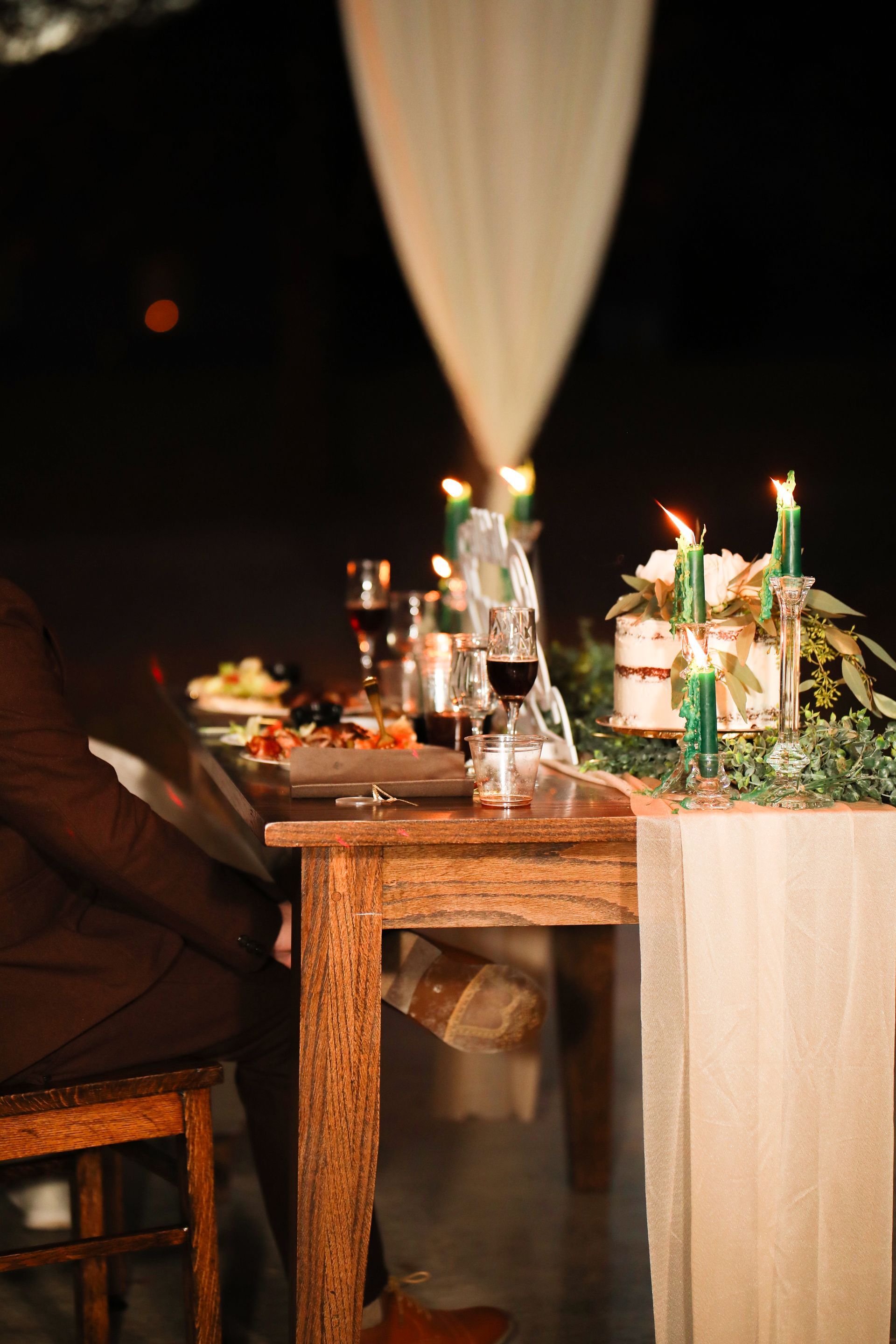 A couple is sitting at a table with candles and wine glasses.