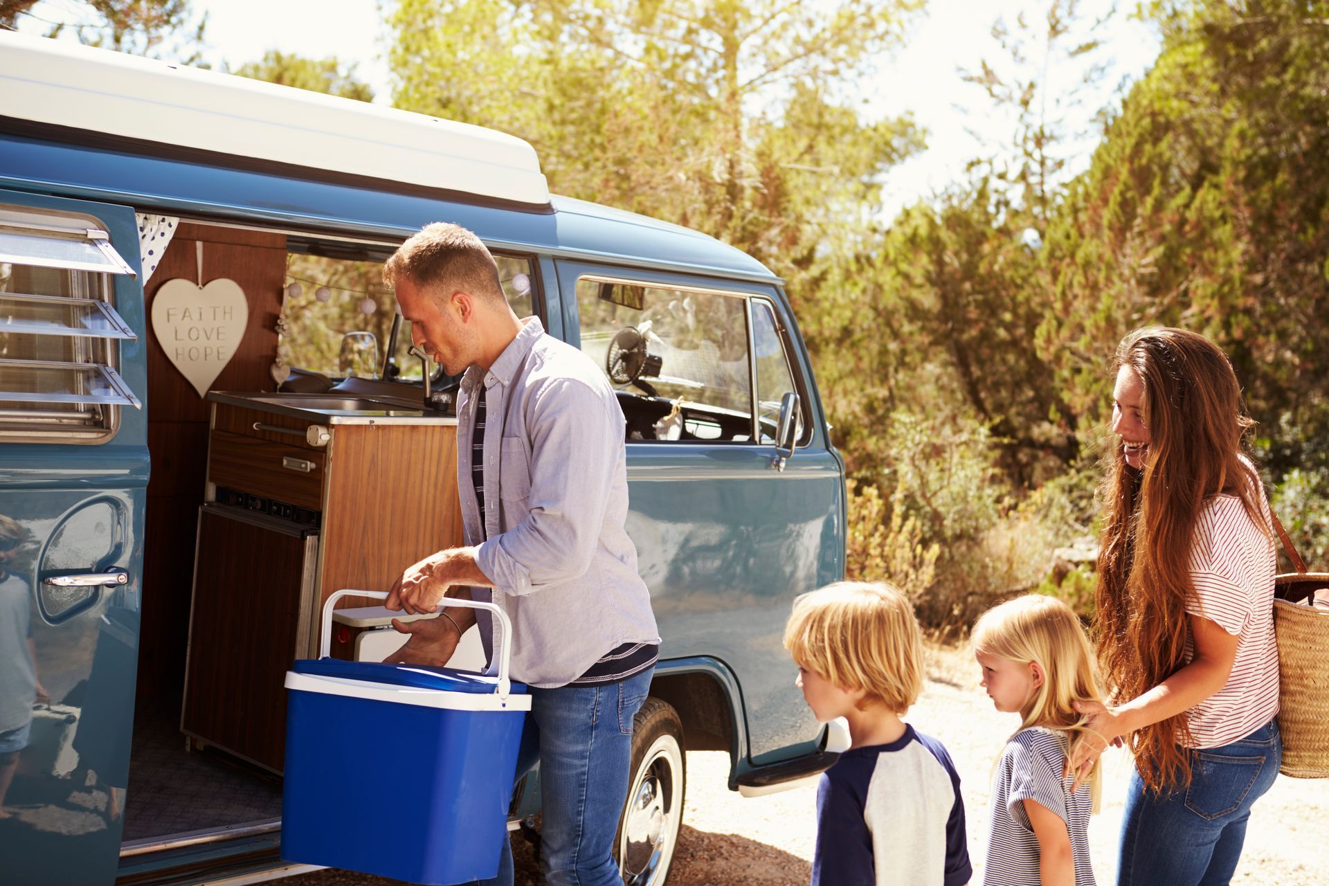 A family is standing in front of a camper van.