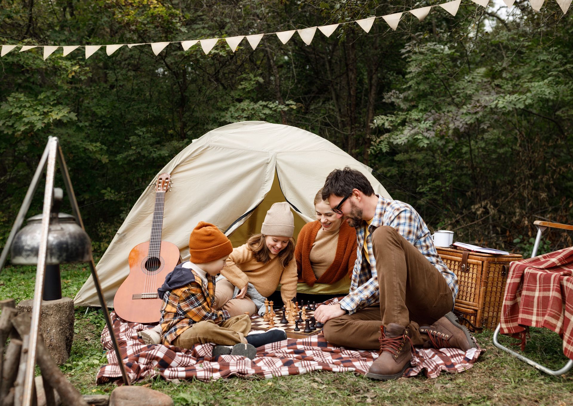 A group of people are sitting on a blanket in front of a tent.