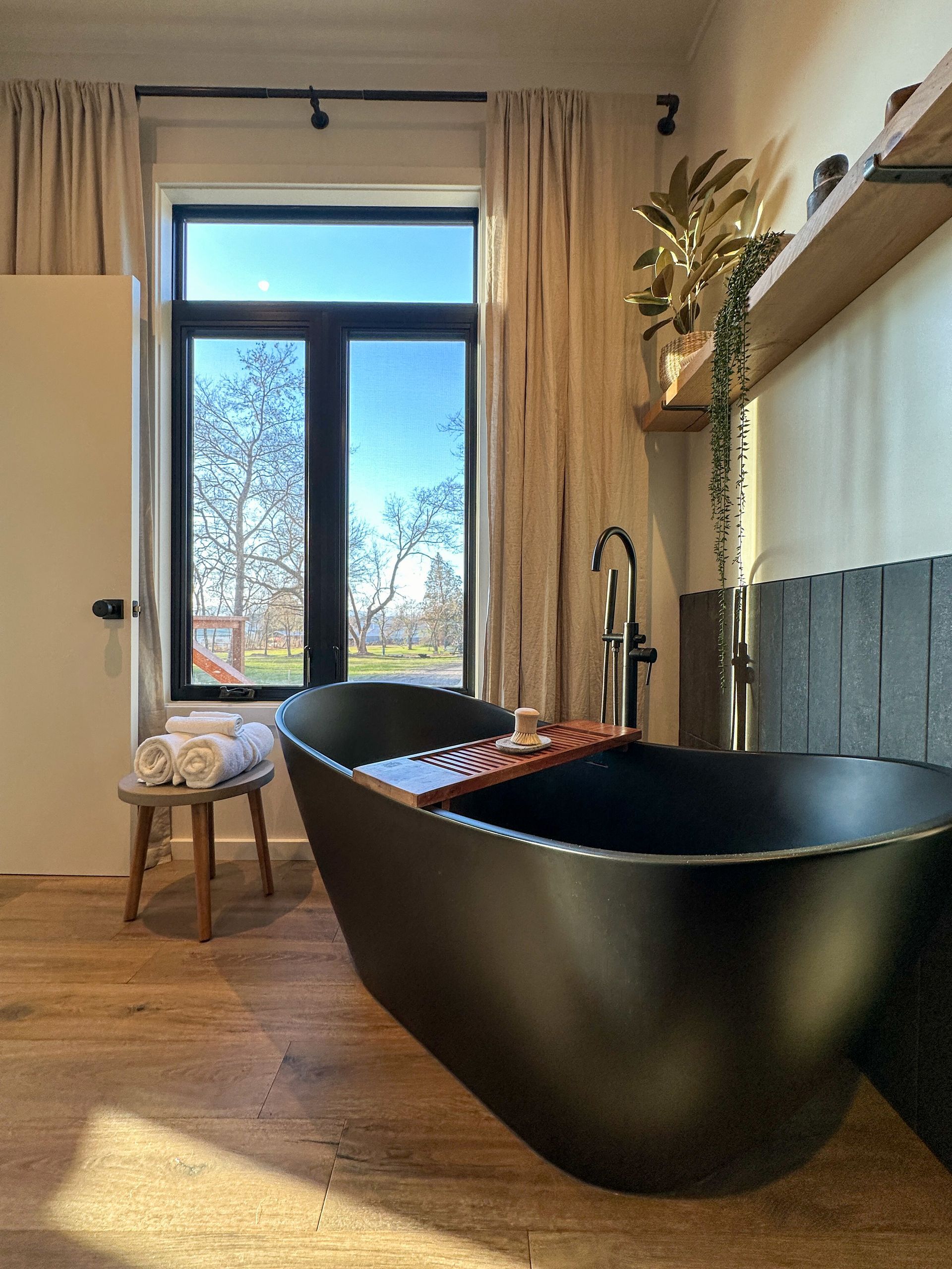 A bathroom with a black bathtub and a window.