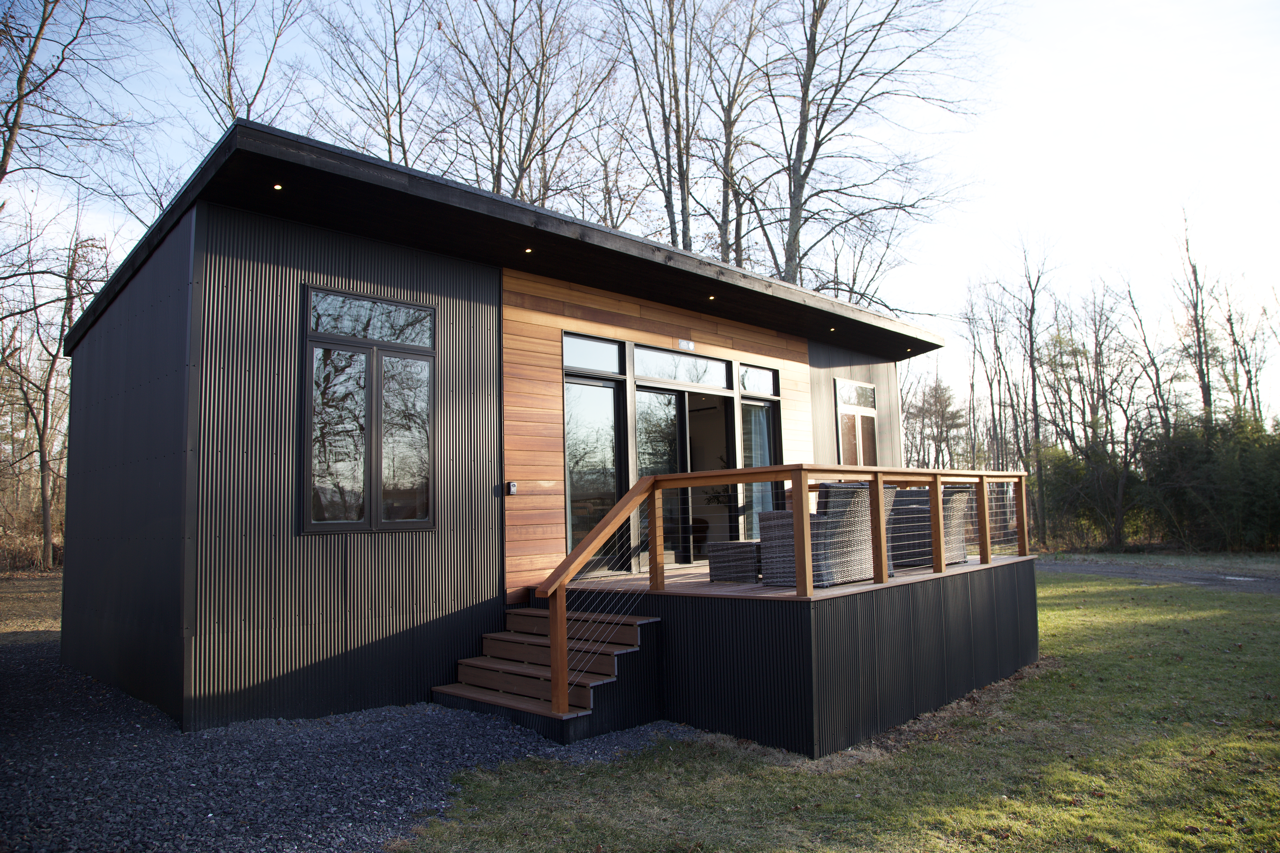 A small house with a deck and stairs in front of it.