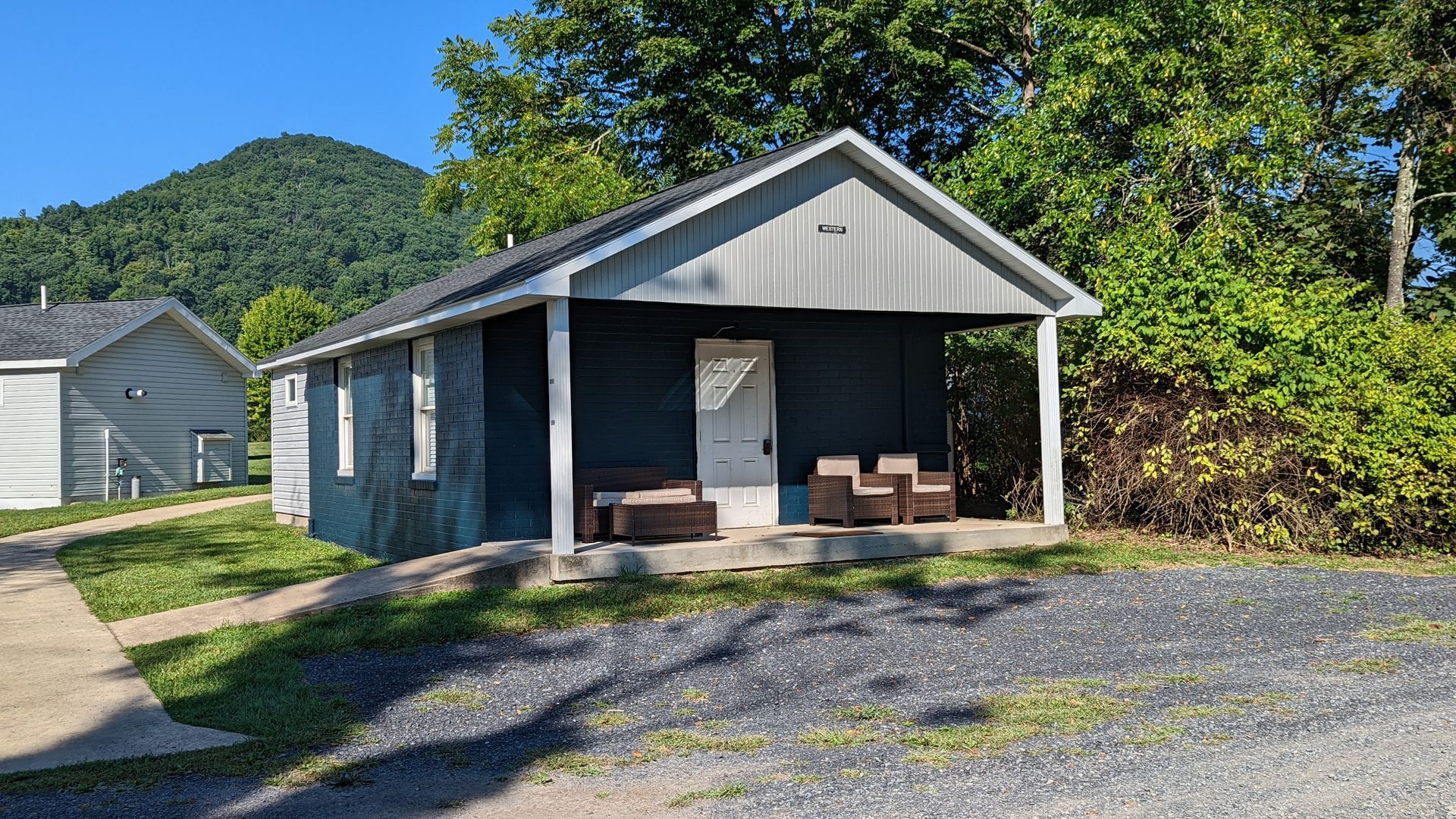 A small house with a porch and a mountain in the background.