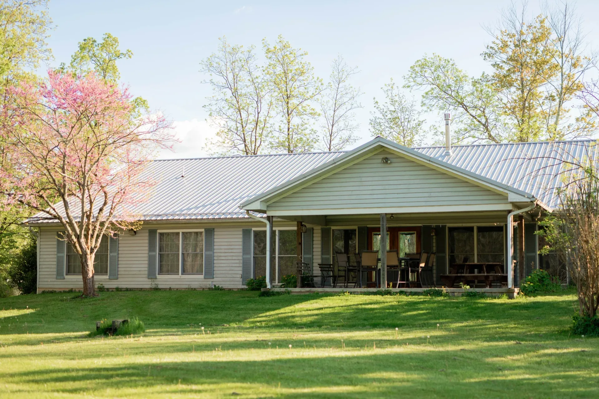 A white building with a porch and trees in front of it.