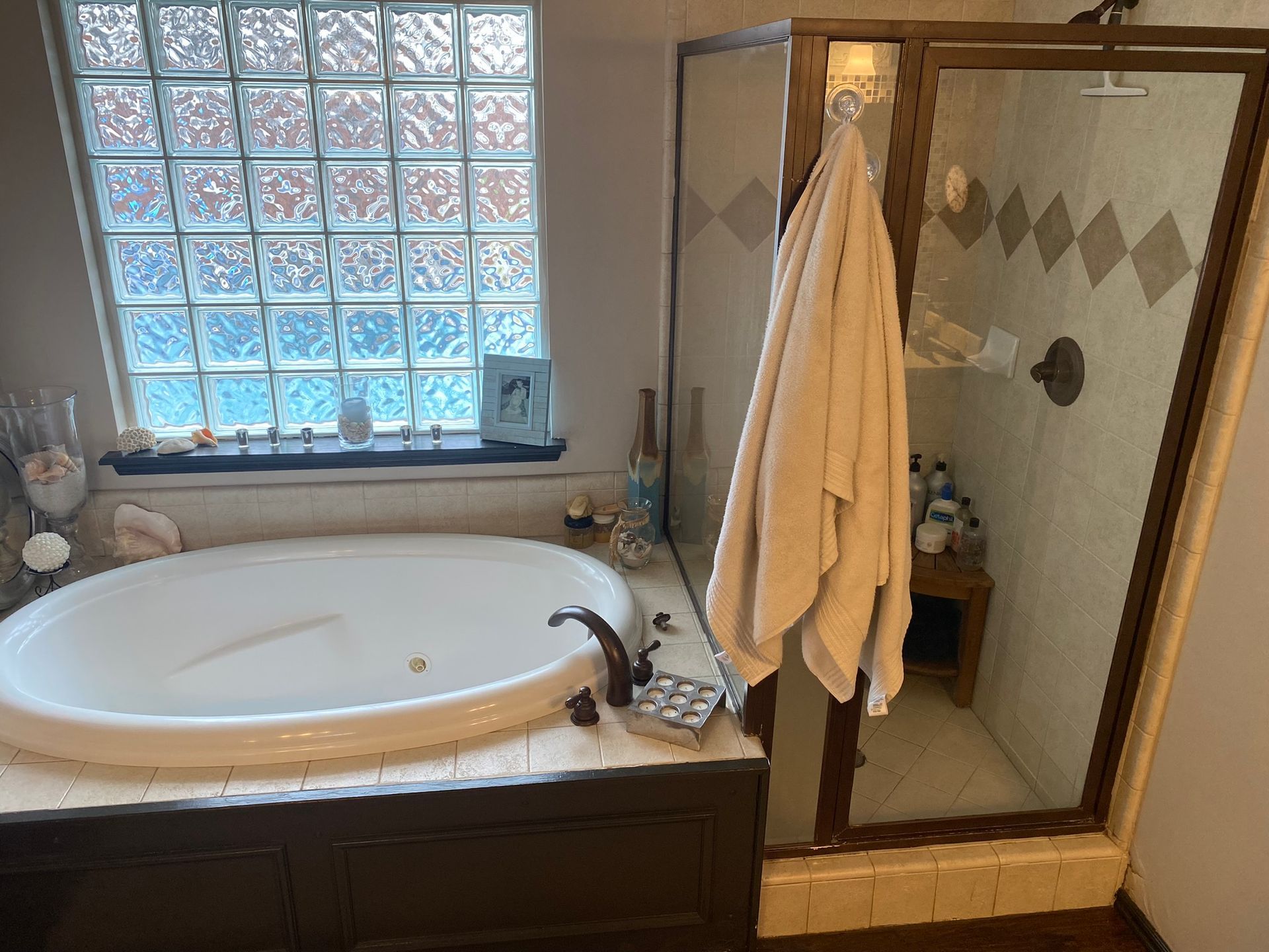Bathroom with a soaking tub, shower, and glass block window. A towel hangs on the shower door.