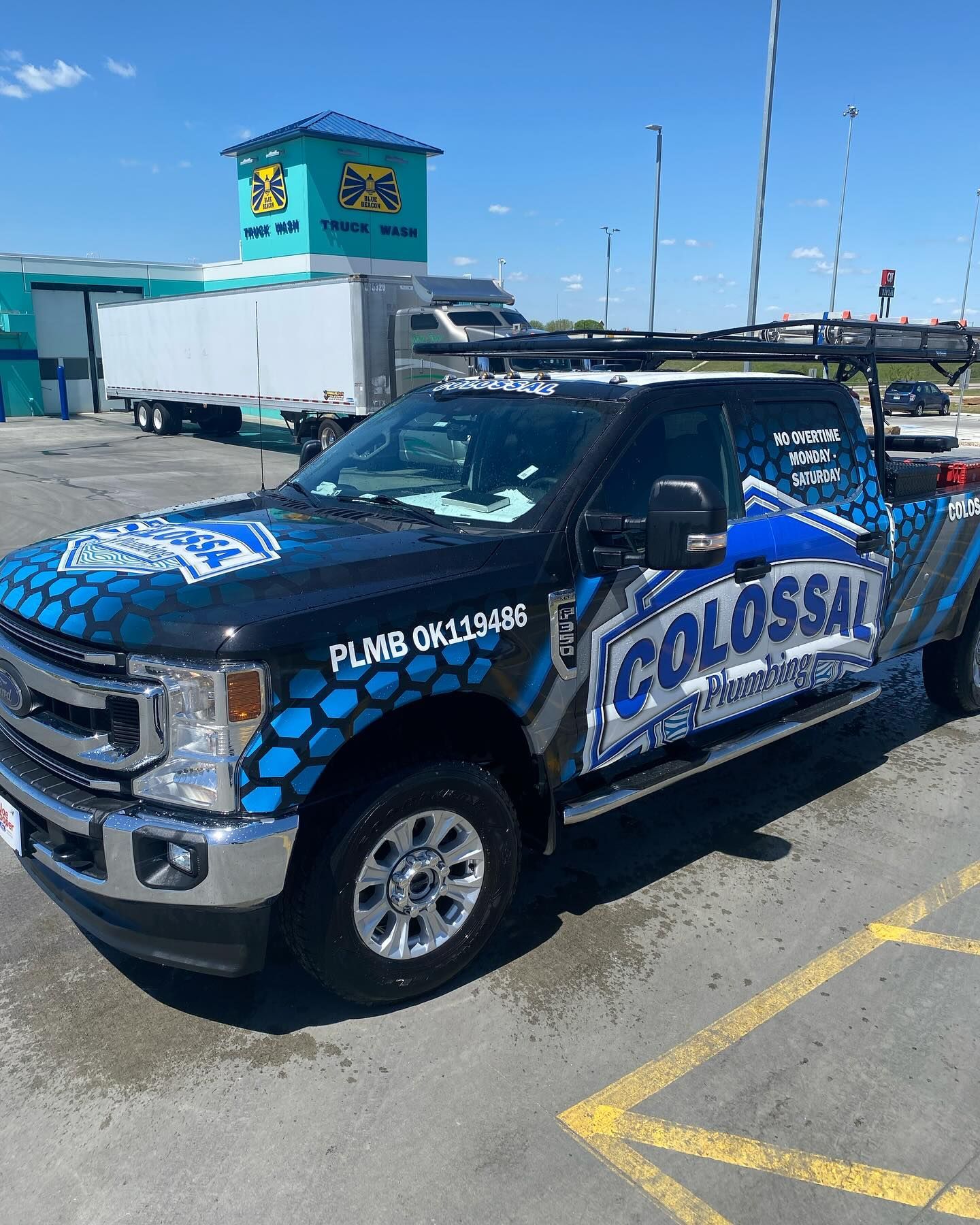 Colossal Plumbing truck with blue and black graphics parked near a building.