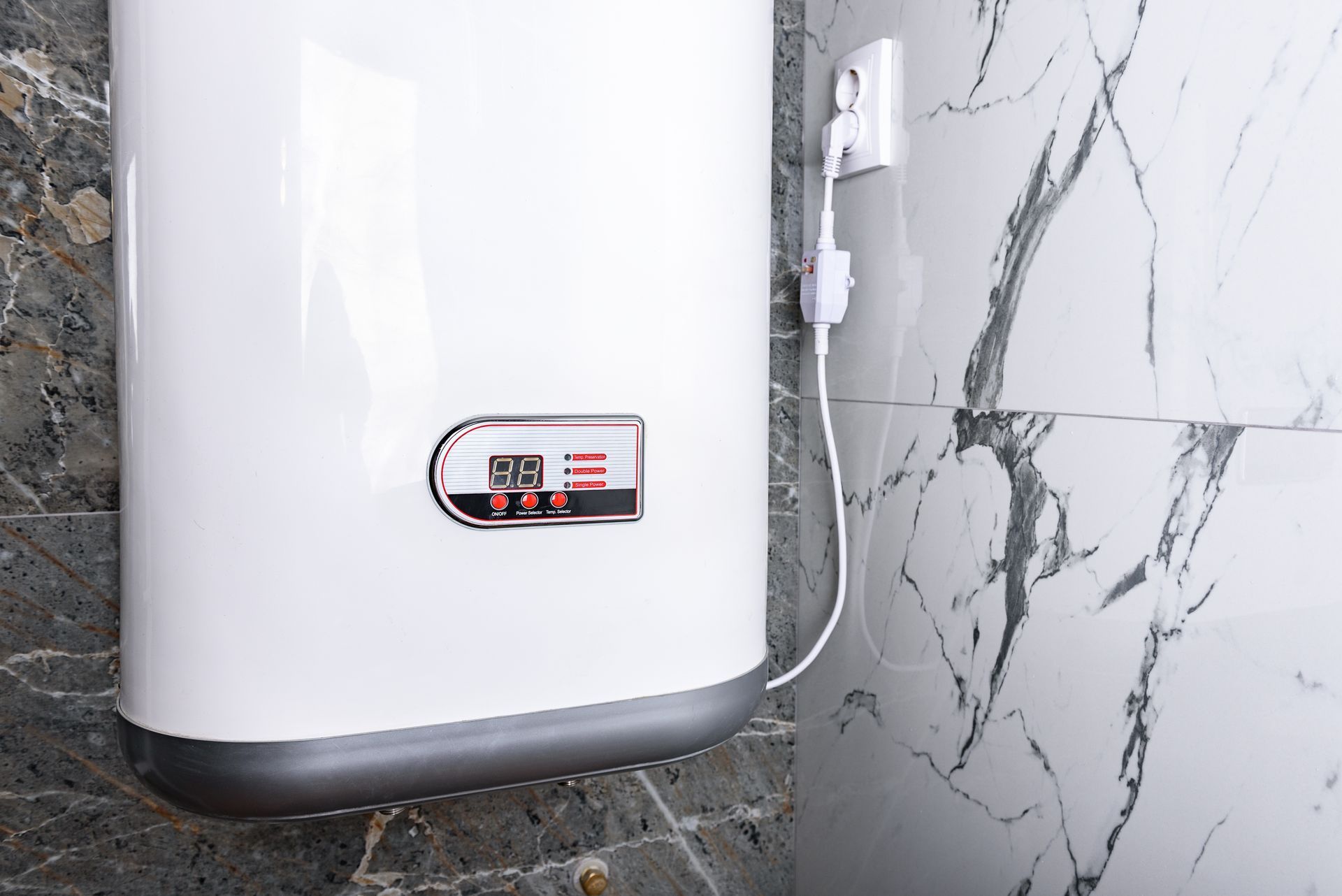 White water heater mounted on marble tile wall, connected to power outlet.